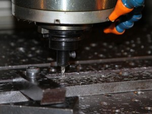 CNC machine being used to drill hole in fabricated metal bar